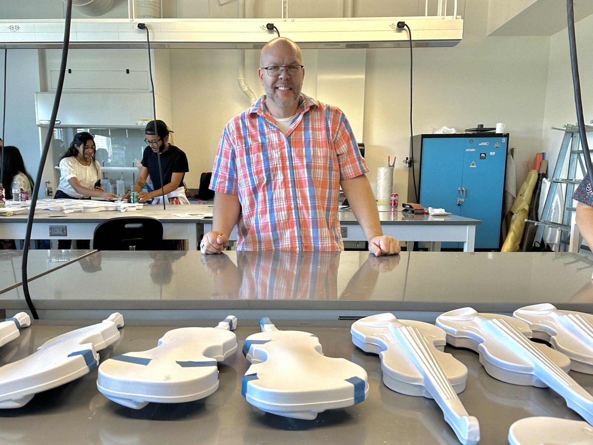 Professor standing behind a table with 3D printed violins