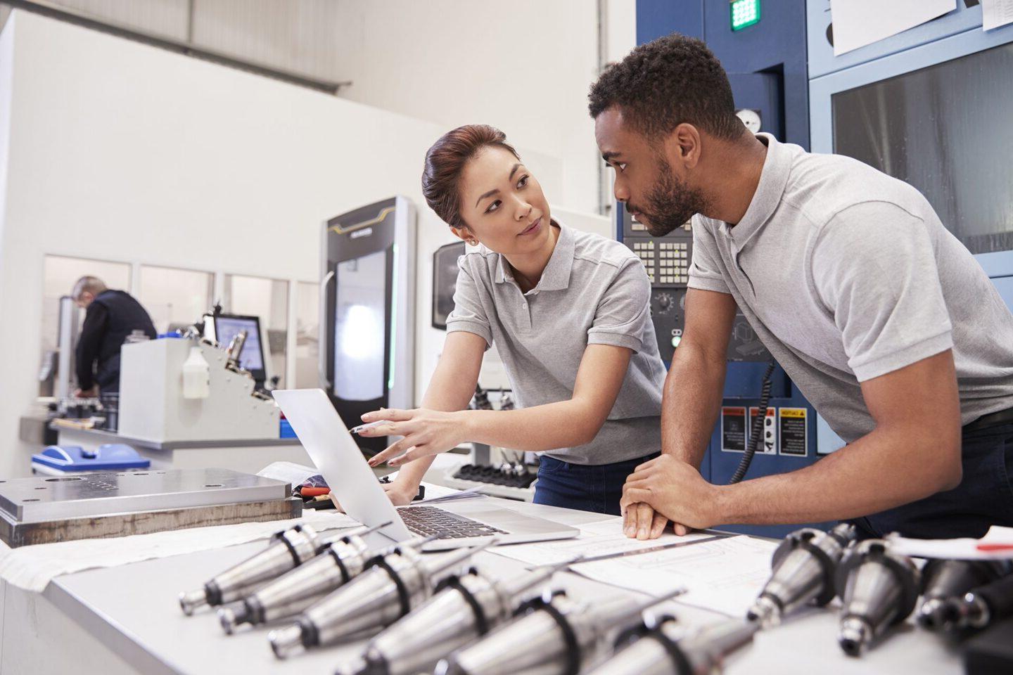 Two Engineers Using CAD Programming Software On Laptop